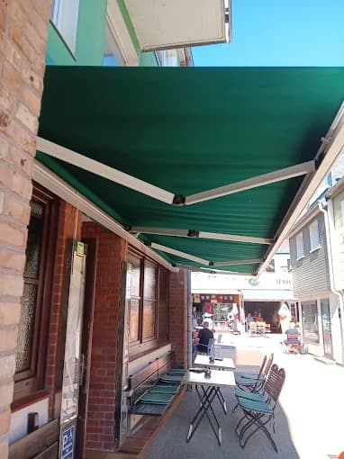 Grüne Gelenkarmmarkise über Gastro-Bereich